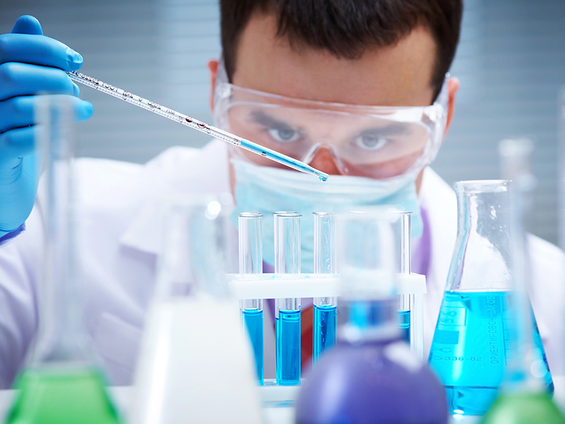 Investigator checking test tubes. Man wears protective goggles
